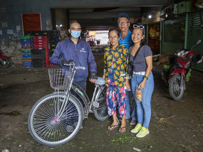 Anh Thắng cùng những người bạn trao tặng chiếc xe đạp đã được làm mới cho bà Út đang làm việc ở chợ đầu mối nông sản Thủ Đức (TP.HCM). Ảnh: N.NHI