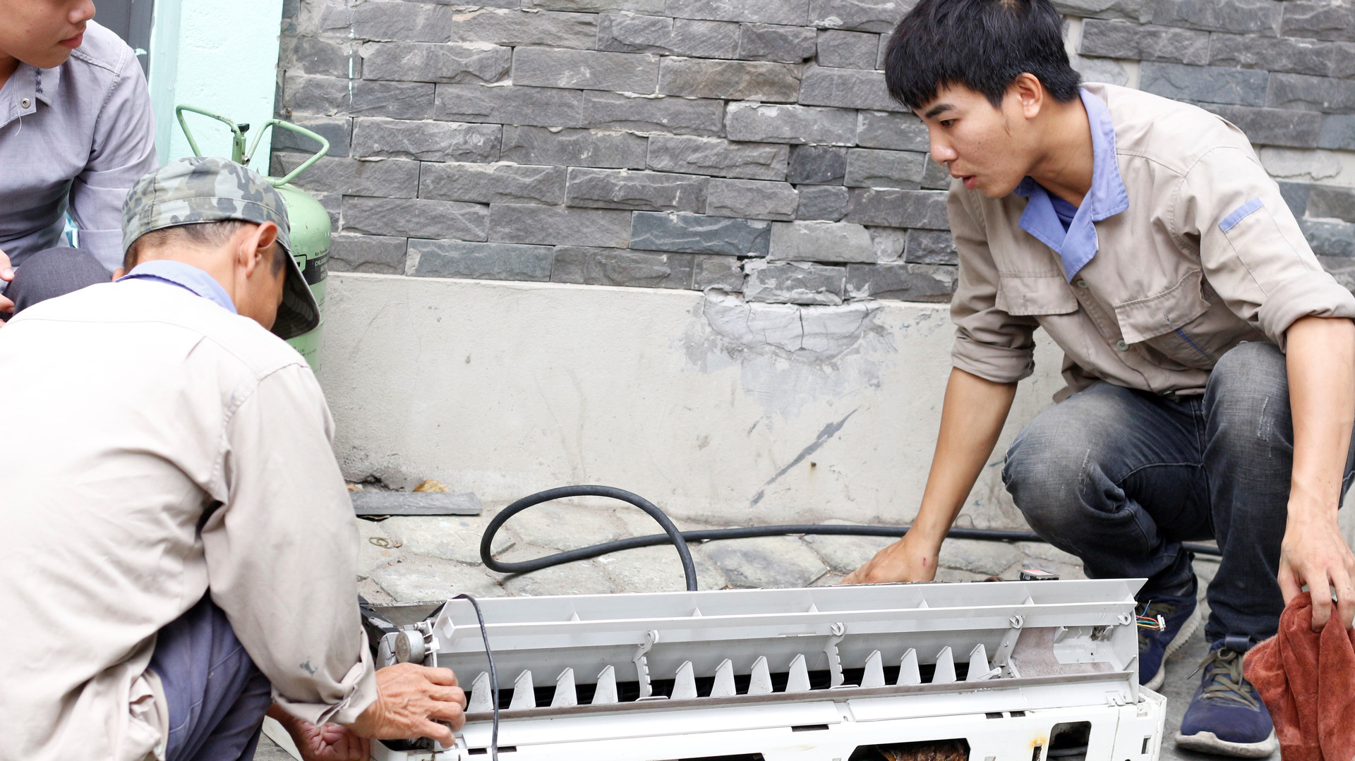 Chú Hùng, 45 tuổi, đồng nghiệp của anh Đức đang vệ sinh vỏ nhựa điều hòa.