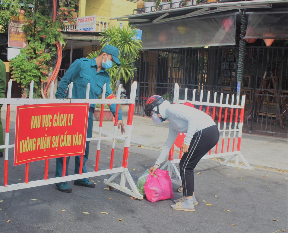 Người dân bên ngoài đưa thực phẩm qua chốt chặn ở khu phố An Hội.