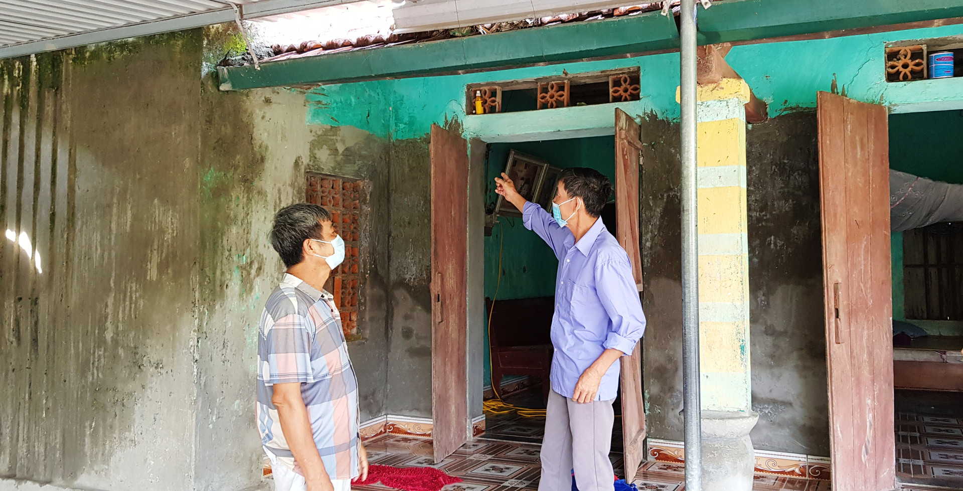 Ông Trần Văn Hợp (bên trái) bức xúc trước căn nhà cấp 4 cũ nát của mình mà không được sửa chữa.
