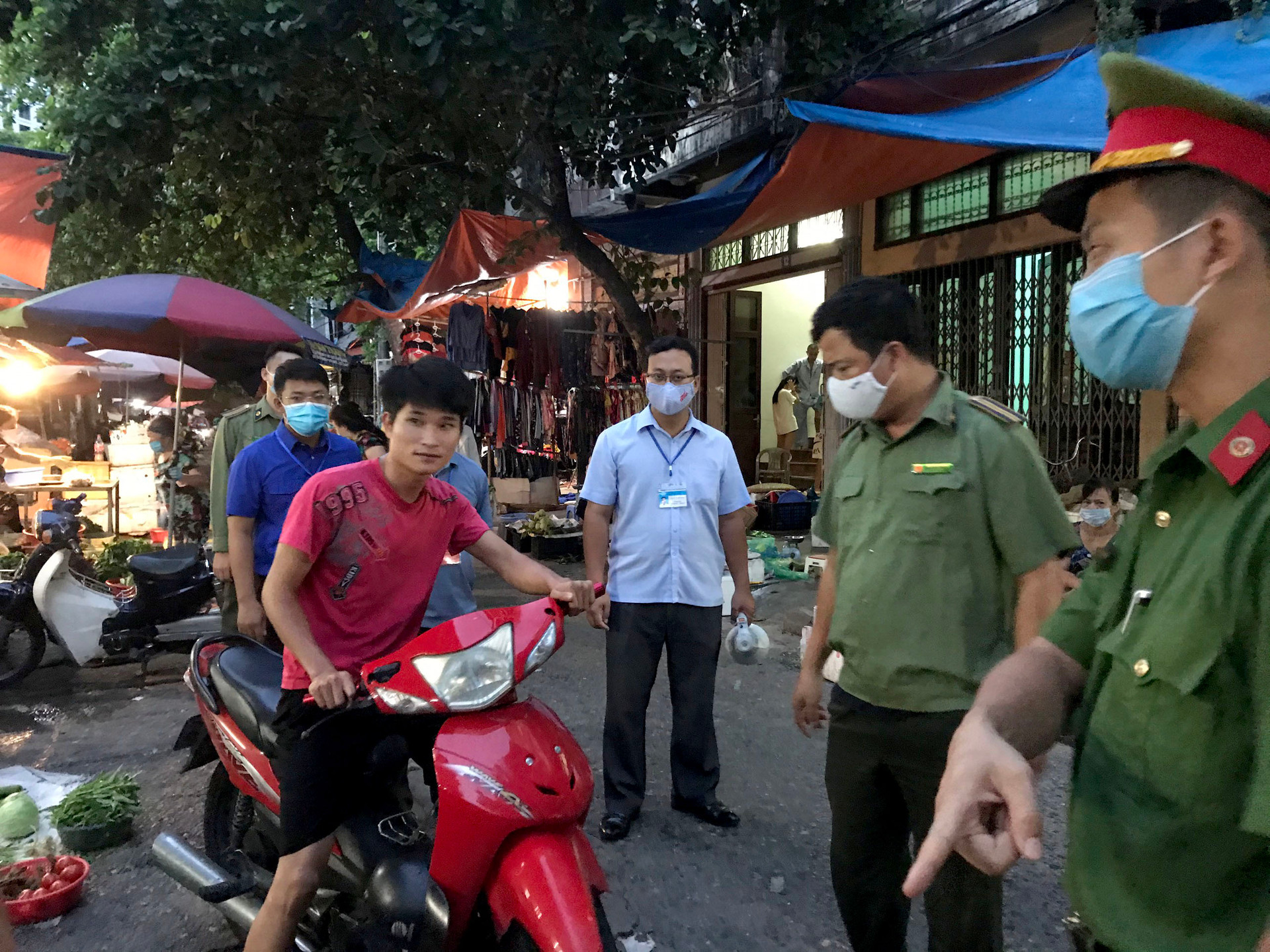 Lực lượng chức năng phường Bạch Đằng nhắc nhở một trường hợp người dân không đeo khẩu trang khi đi chợ.