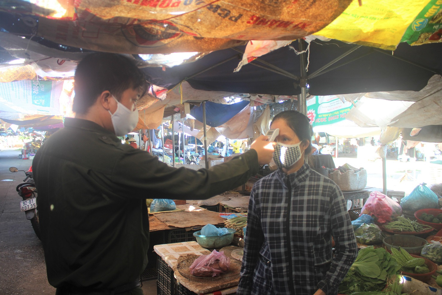 Anh Bình đo thân nhiệt cho tiểu thương chợ Vườn Lài.