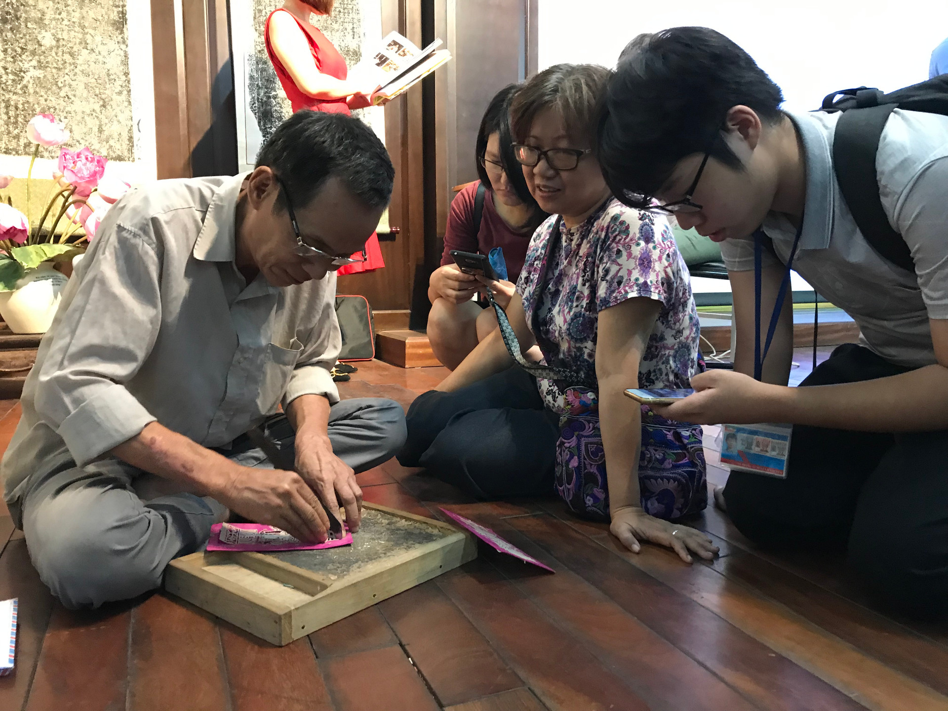Nghệ nhân Nguyễn Đăng Giáp giới thiệu nghề làm tranh trổ giấy của làng Đông Hồ cho du khách Ảnh: Thanh Xuân.