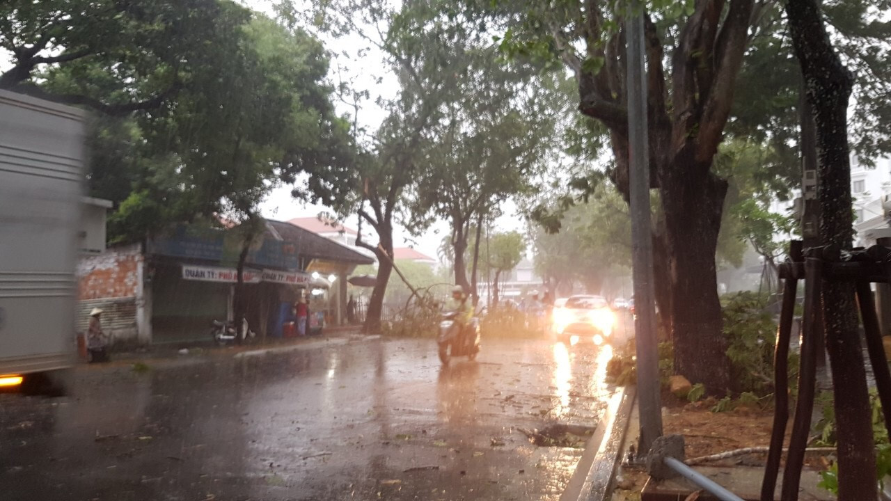 Người đi đường phải tấp vội vào lề đường, hiên nhà để tránh mưa to gió lớn lúc 9h sáng nay 18/9 tại Huế. Ảnh: Dân trí.