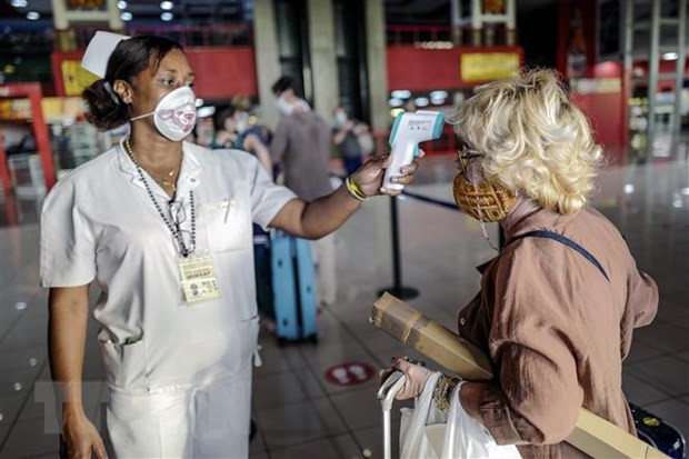 Nhân viên y tế Cuba kiểm tra thân nhiệt du khách nhằm ngăn ngừa dịch COVID-19 lây lan, tại một nhà khách ở Havana. (Ảnh: AFP/TTXVN).