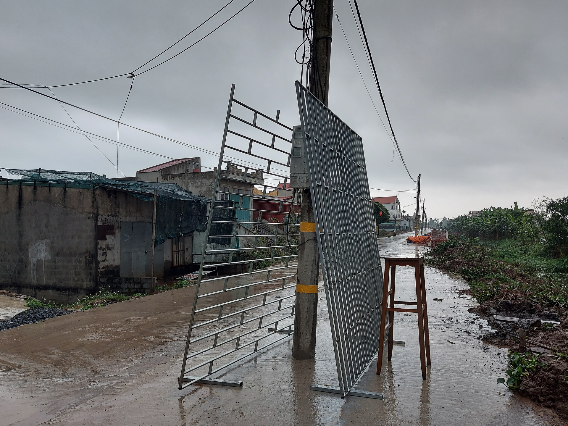 Một người dân kê những tấm mái xe bằng sắt lên cây cột điện trong ngày mưa gió.