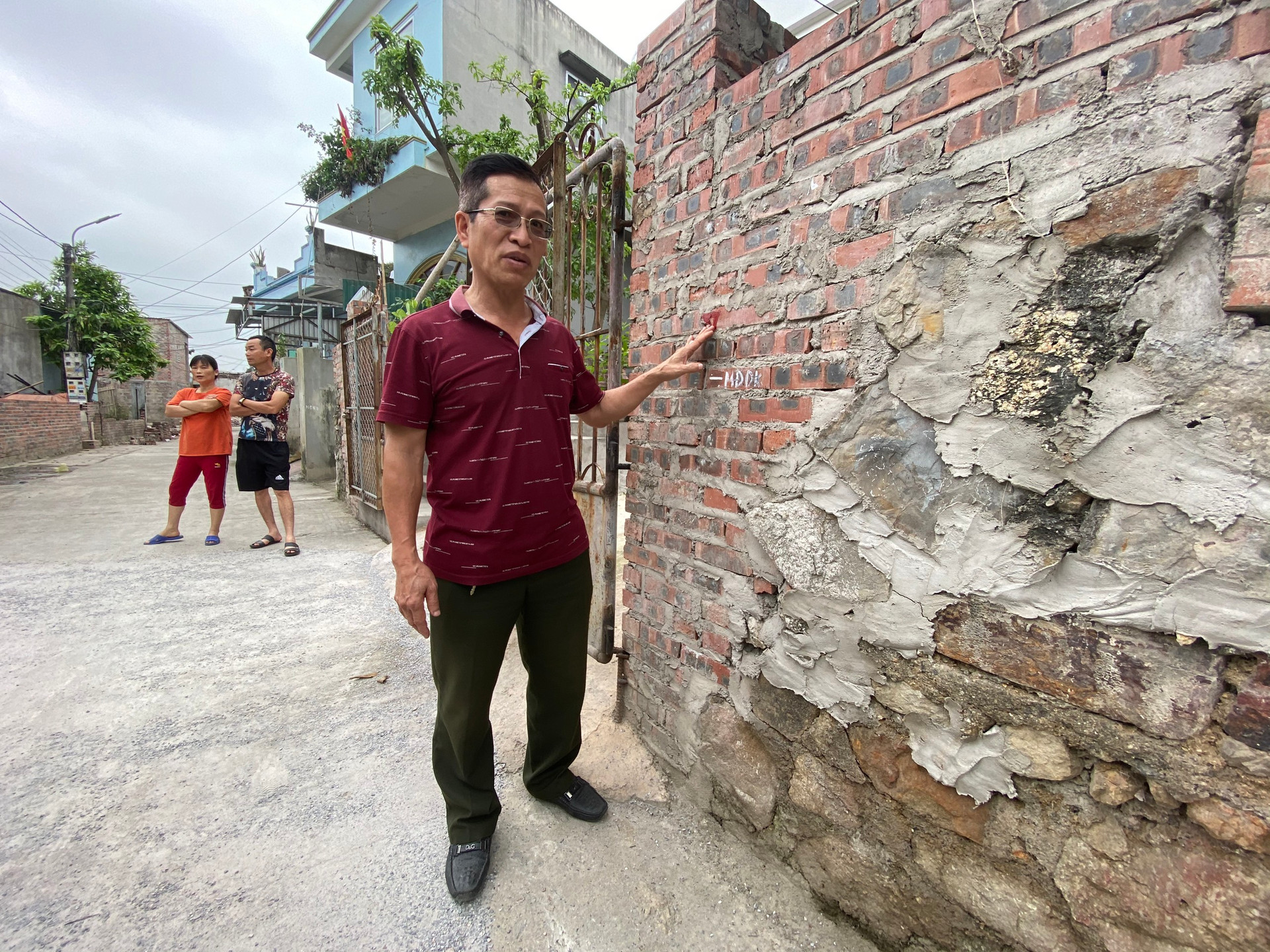 Ông Nguyễn Hoài Nam, tổ trưởng tổ 65, khu 7 đứng bên cạnh vạch mốc nước ngập cao kỉ lục mà khu vực này từng gánh chịu. 