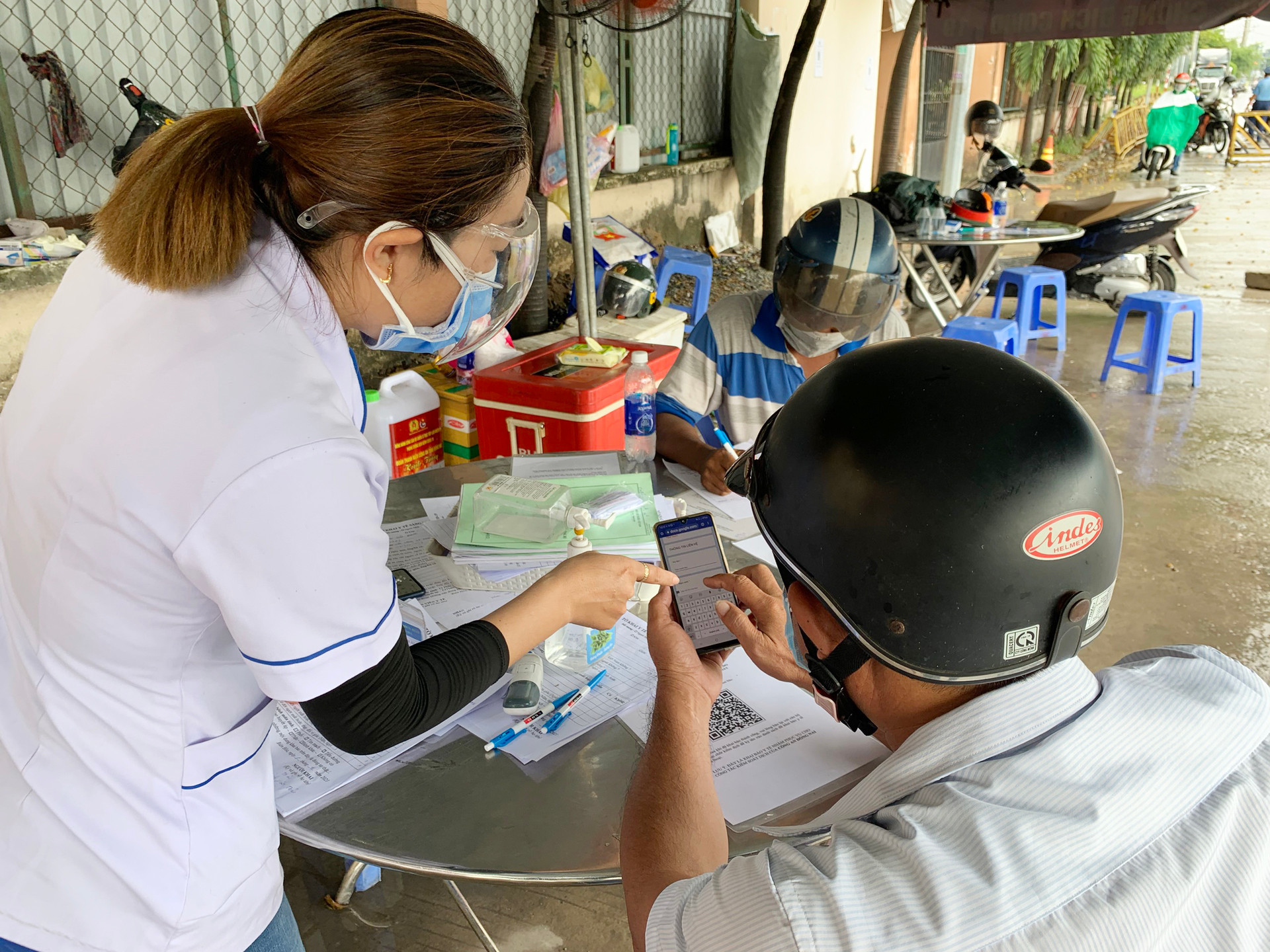 Chị Trần Thị Minh Ái, thành viên tại chốt trực phụ trách nhiệm vụ kiểm tra y tế tại chốt cầu Hóa An hướng dân người dân khai báo y tế.