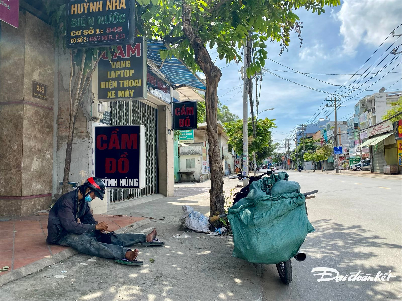 Một người đàn ông mệt mỏi giữa nắng gắt ngồi nghỉ bên vỉa hè đường Nơ Trang Long (quận Bình Thạnh).