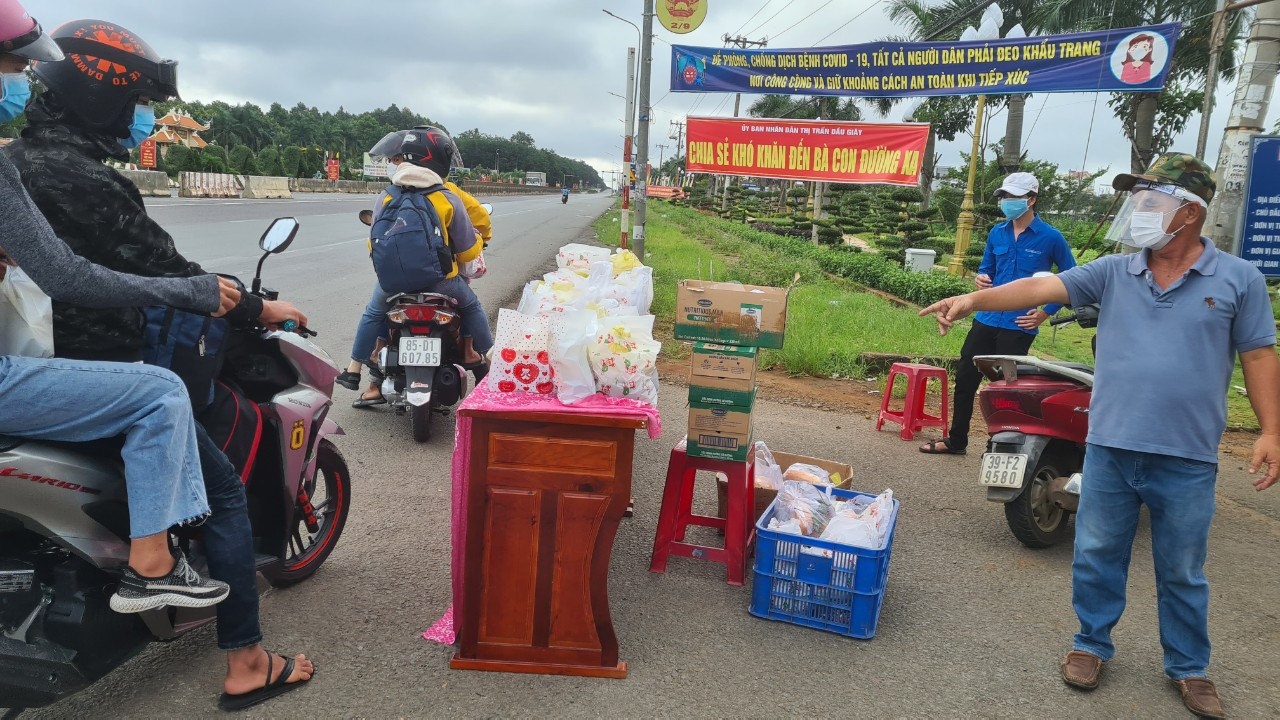 Người dân đi xe máy về quê đang dừng lại điểm phát đồ ăn, nước uống miễn phí trên Quốc lộ 1A đoạn qua Thị trấn Dầu Giây, huyện Thống Nhất - Ảnh: Mạnh Thìn.