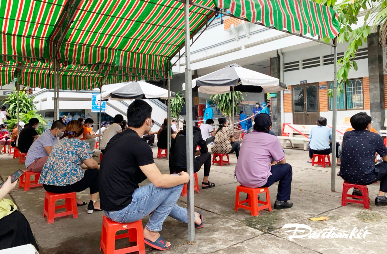 Người dân chờ làm thủ tục tại điểm tiêm (sáng ngày 13/8, tại trường THCS Nguyễn Huệ, 243 đường Hoàng Diệu, P8, Q4, TPHCM) - Ảnh: Hữu Vinh