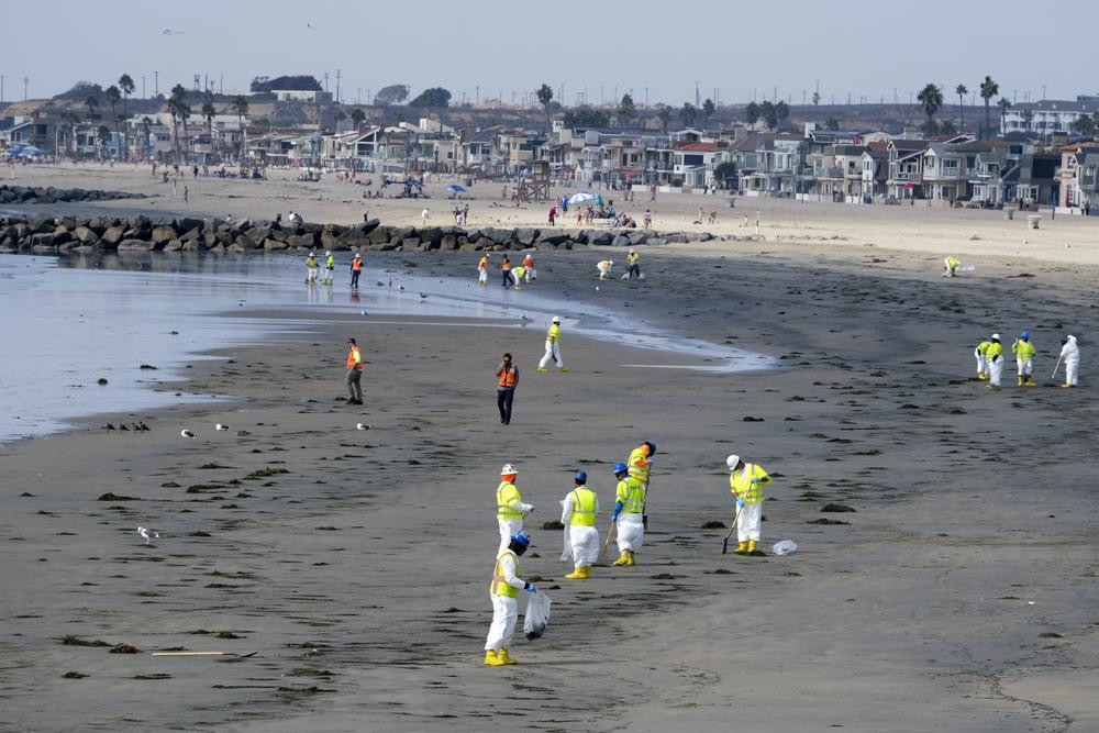 Công nhân mặc đồ bảo hộ dọn dẹp bãi biển bị ô nhiễm sau sự cố tràn dầu ở Newport Beach, California, Mỹ. Ảnh: AP.