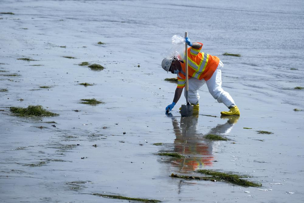Một công nhân trong bộ đồ bảo hộ đang dọn dẹp bãi biển bị ô nhiễm sau sự cố tràn dầu ở Newport Beach, California, Mỹ. Ảnh: AP.