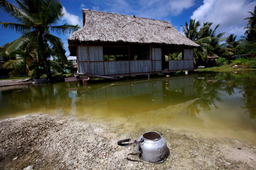 Một ngôi nhà bỏ hoang bị ảnh hưởng bởi mực nước biển dâng cạnh một đầm phá nhỏ gần làng Tangintebu, Nam Tarawa ở quốc đảo Kiribati, miền trung Thái Bình Dương. Ảnh: Reuters.