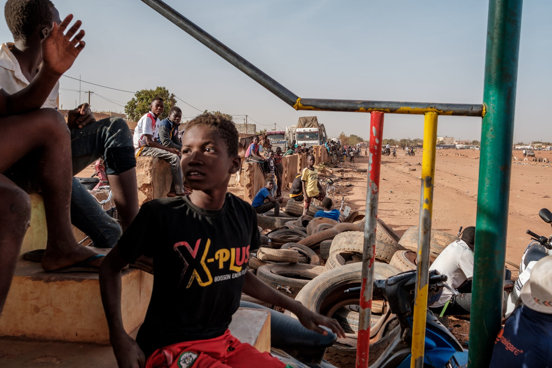 Khán giả ngồi trên khán đài bao quanh đường đua trong trường đua ngựa Ouagadougou - một đường đua đầy bụi được lót bằng lốp xe. Ảnh: Guy Peterson / The Guardian.