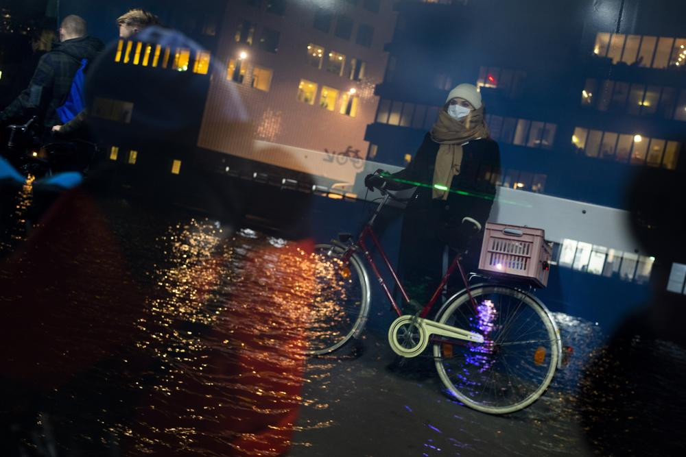 Hình ảnh một người phụ nữ đeo khẩu trang phản chiếu qua cửa sổ của một chuyến phà qua sông IJ ở Amsterdam, Hà Lan. Ảnh AP / Peter Dejong.