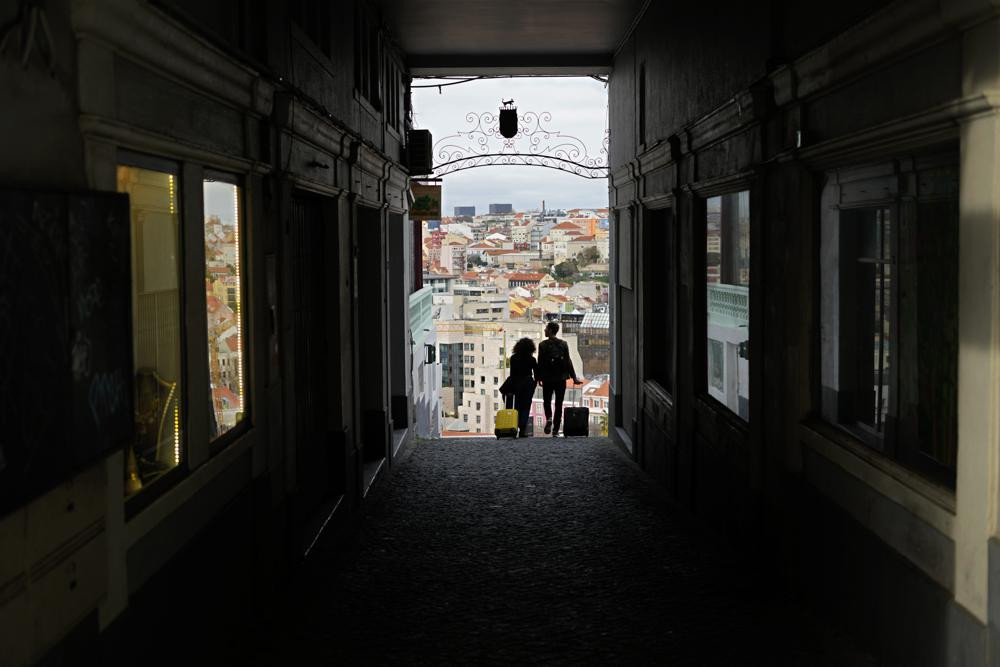 Một cặp đôi kéo va li du lịch dọc theo một con hẻm ở Lisbon. Ảnh AP / Armando Franca.