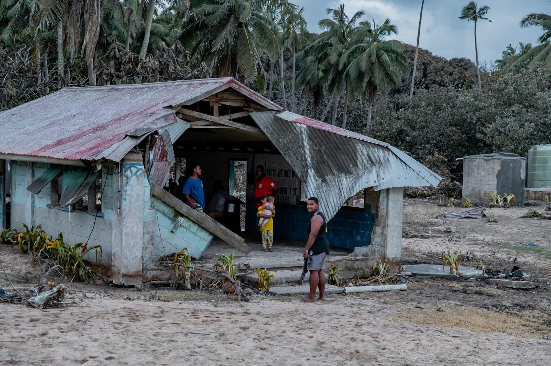 Người dân địa phương chờ mặt trời lặn tại một hội trường cộng đồng bị hư hại nặng nề trên đảo Fonoi. Ảnh: Leki Lao / The Guardian.