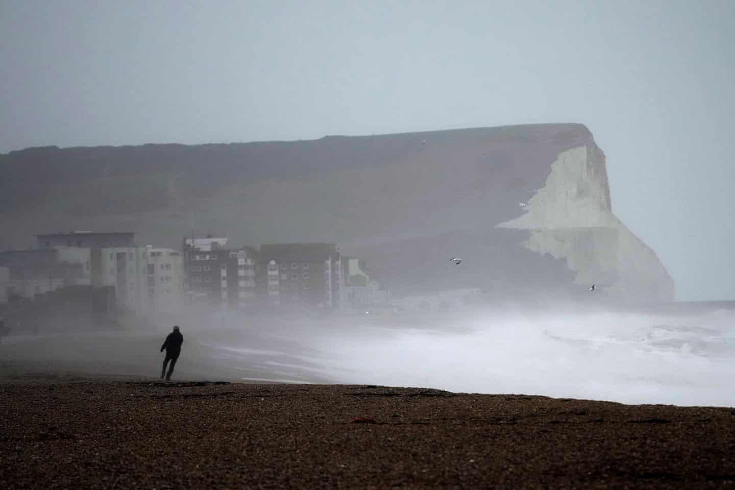 Một người đi bộ trên bãi biển Seaford, khi cơn bão Eunice ập đến. Hàng triệu người Anh đang bị thúc giục hủy bỏ kế hoạch du lịch và ở trong nhà vì lo ngại gió lớn và các mảnh vỡ bay. Ảnh: Matt Dunham / AP.