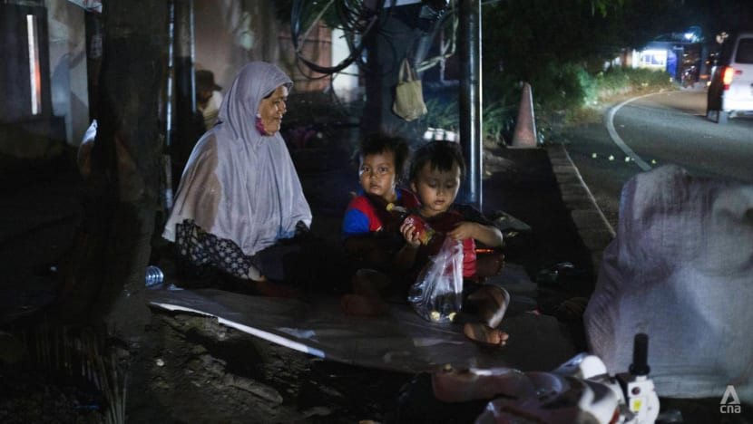 Người phụ nữ cùng hai đứa con trên vỉa hè cạnh con phố đông đúc ở Jakarta, Indonesia. Ảnh: CNA.