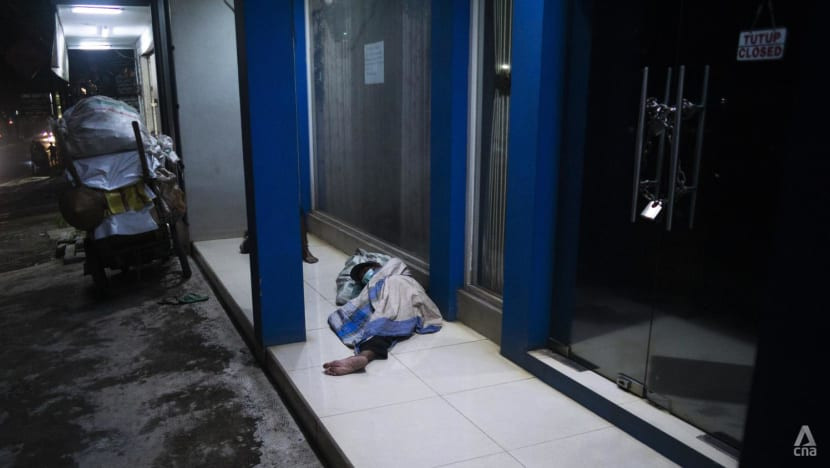 Hai người nhặt rác ngủ trước một cửa hàng đồ nội thất đã đóng cửa ở Jakarta, Indonesia. Ảnh: CNA.