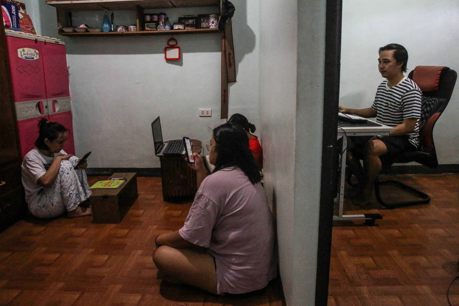 Dominic Lumabi (bên phải) chơi Axie Infinity trên máy tính của anh tại nhà ở ngoại ô thủ đô Manila vào tháng 12/2021. Ảnh: Japan Times.