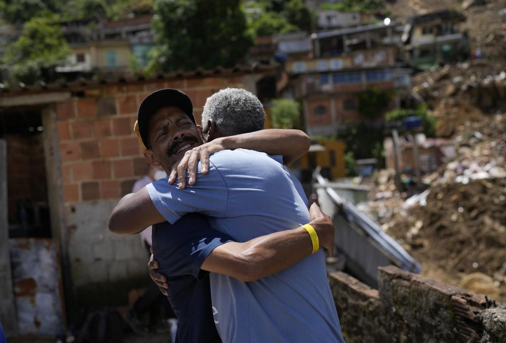 Ông Condé cũng người bạn an ủi nhau tại địa điểm xảy ra trận lở đất kinh hoàng tại Morro da Oficina. Ảnh: AP.