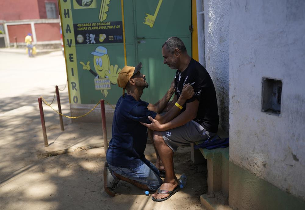 Ông Condé cùng người bạn, ông Adalto da Silva cùng chia sẻ nỗi đau tại một góc đường ở thành phố Petropolis. Ảnh: AP.