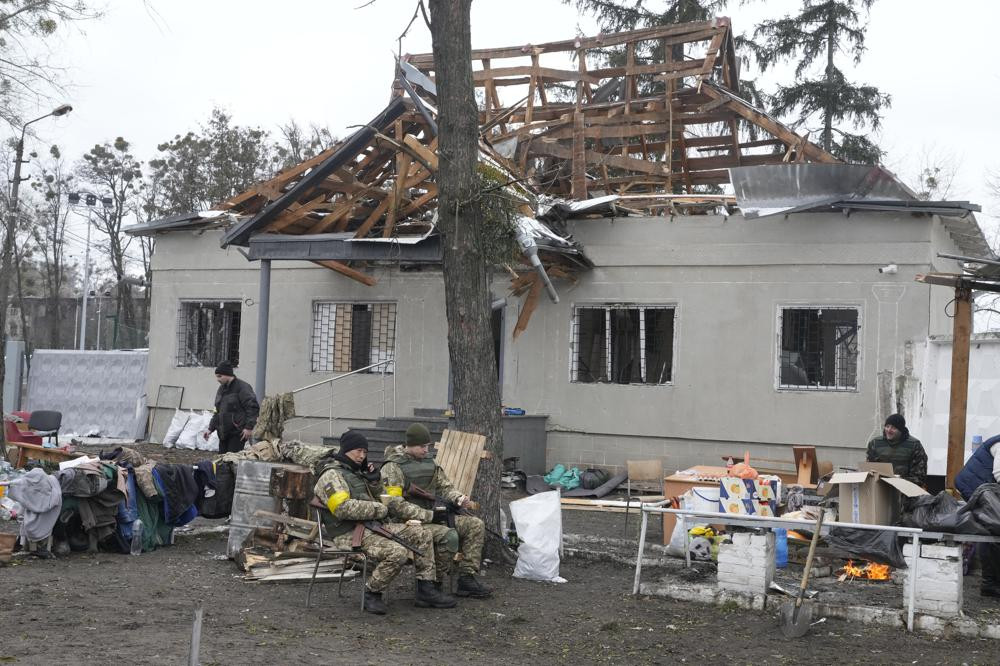 Các quân nhân Ukraine ngồi trước một ngôi nhà bị hư hại gần một trạm kiểm soát ở thành phố Brovary, ngoại ô thủ đô Kiev, Ukraine. Ảnh: AP.