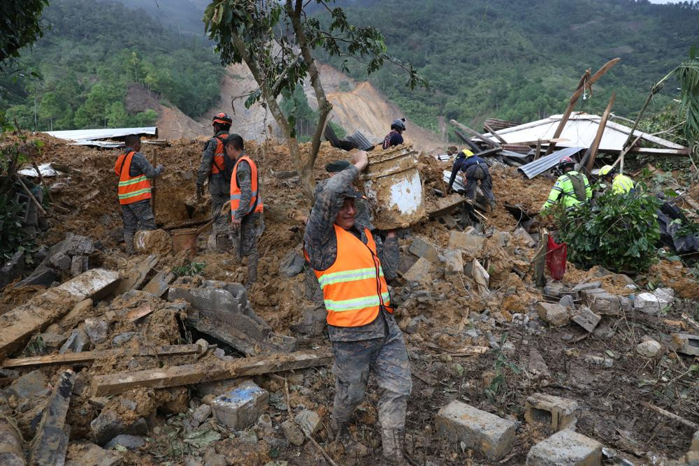 Các thành viên của đội tìm kiếm giúp đỡ những người sống sót trong đống đổ nát của trận lở đất lớn do mưa gây ra ở làng Queja, Guatemala. Ảnh: AP.