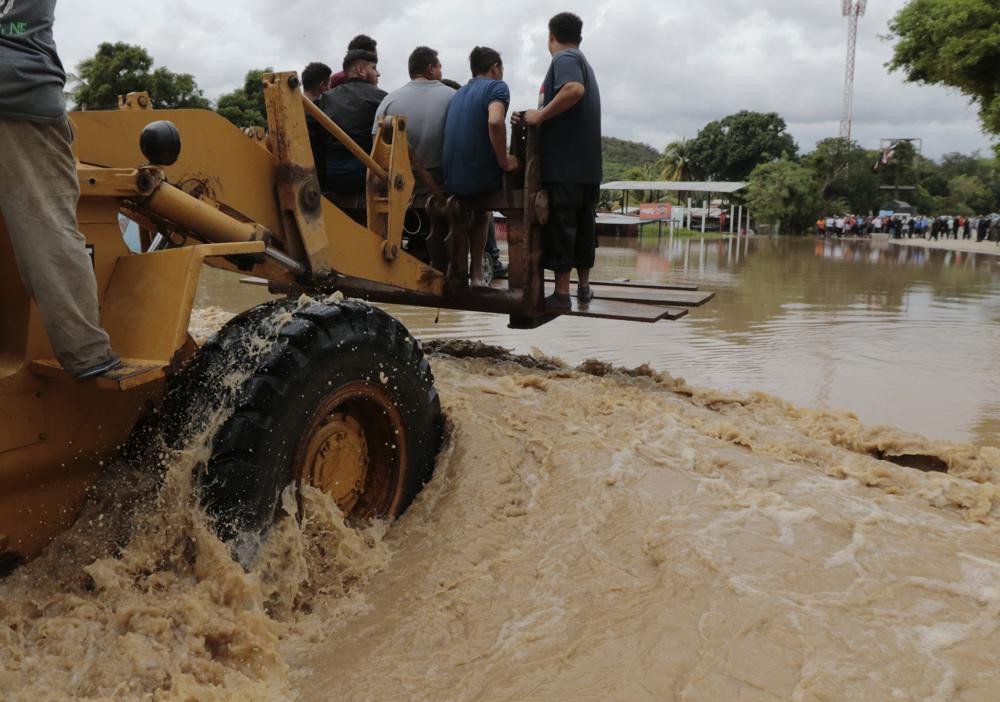 Một chiếc xe nâng hạng nặng vận chuyển người dân qua một khu vực ngập lụt sau khi cơn bão Iota càn quét ở La Lima, Honduras. Ảnh: AP.