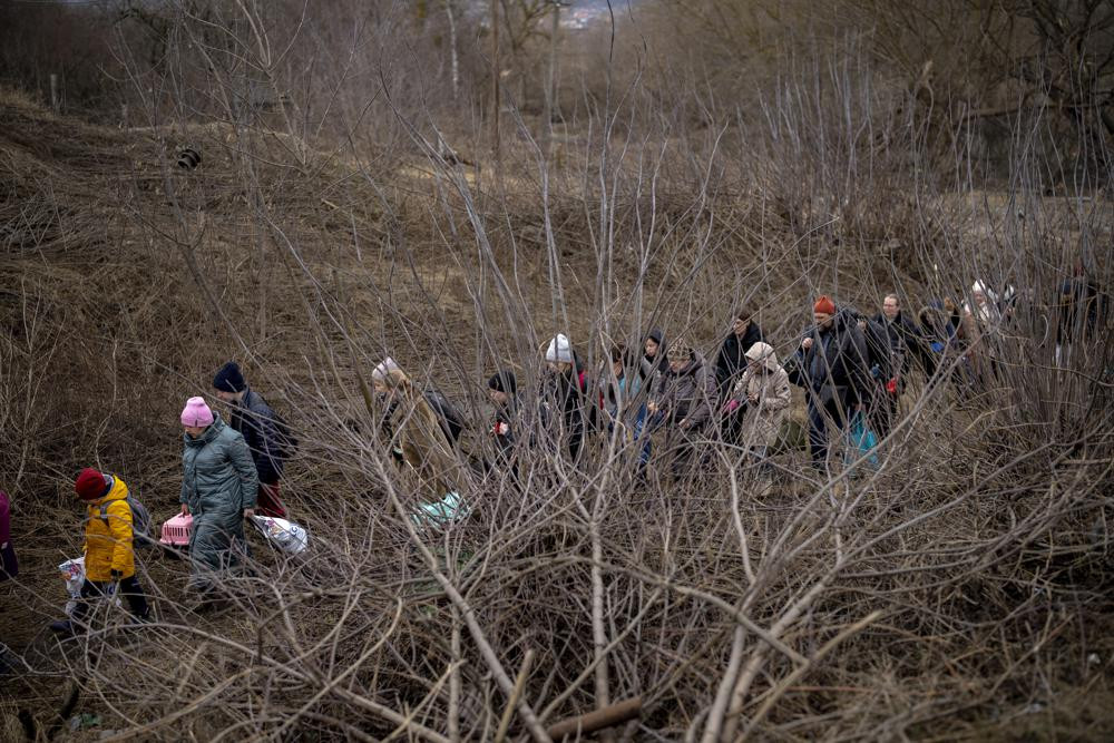 Người dân Ukraine băng qua sông Irpin ở ngoại ô thủ đô Kiev, Ukraine. Ảnh: AP.