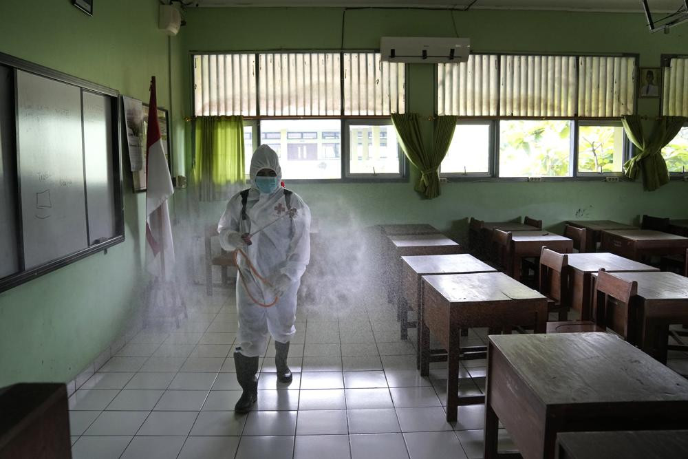 Nhân viên y tế phun thuốc khử trùng bên trong một trường học ở Jakarta, Indonesia. Ảnh: AP.