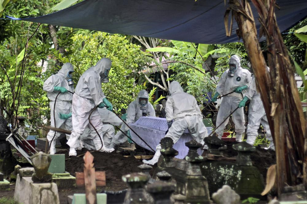 Các công nhân mặc đồ bảo hộ chôn cất một bệnh nhân ở Yogyakarta, Indonesia. Ảnh: AP.