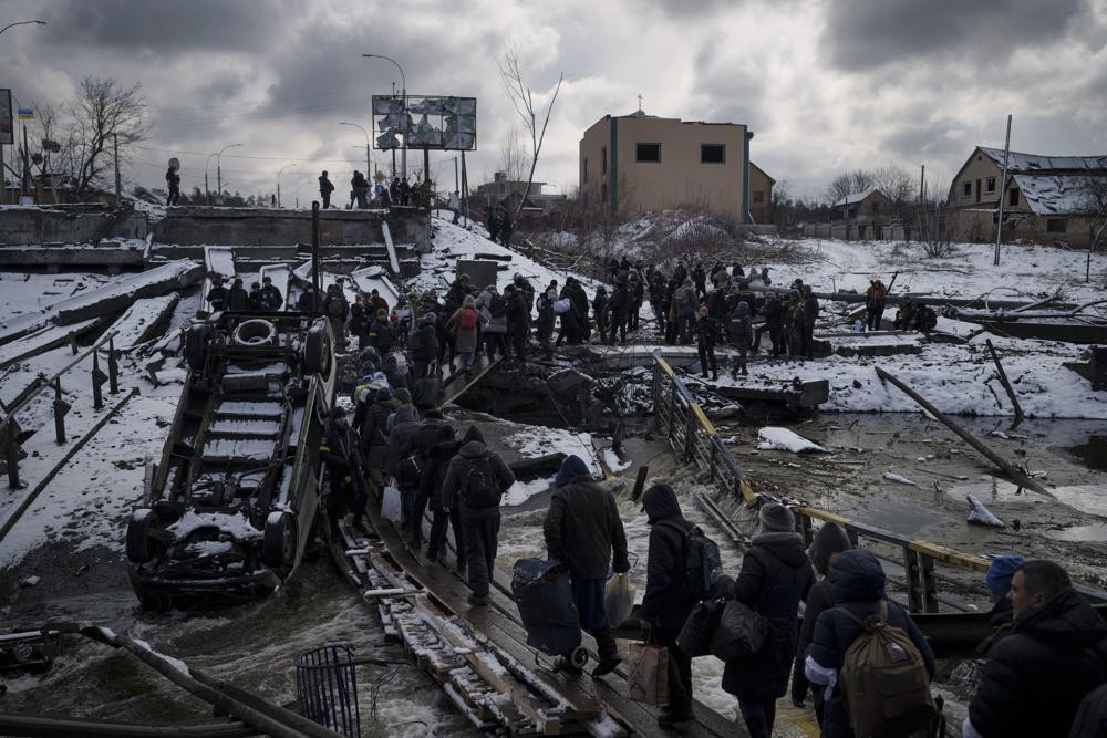 Người dân băng qua một cây cầu bị phá hủy ở Irpin, ngoại ô thủ đô Kiev, Ukraine. Ảnh: AP.