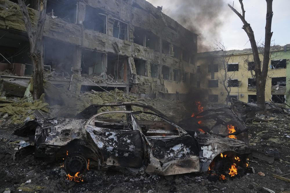 Một chiếc ô tô bị cháy trước một bệnh viện phụ sản ở thành phố Mariupol, Ukraine. Ảnh: AP.
