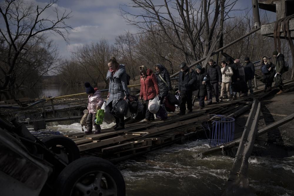 Người dân Ukraine băng qua một cây cầu bị phá hủy ở Irpin, ngoại ô thủ đô Kiev, Ukraine. Ảnh: AP.