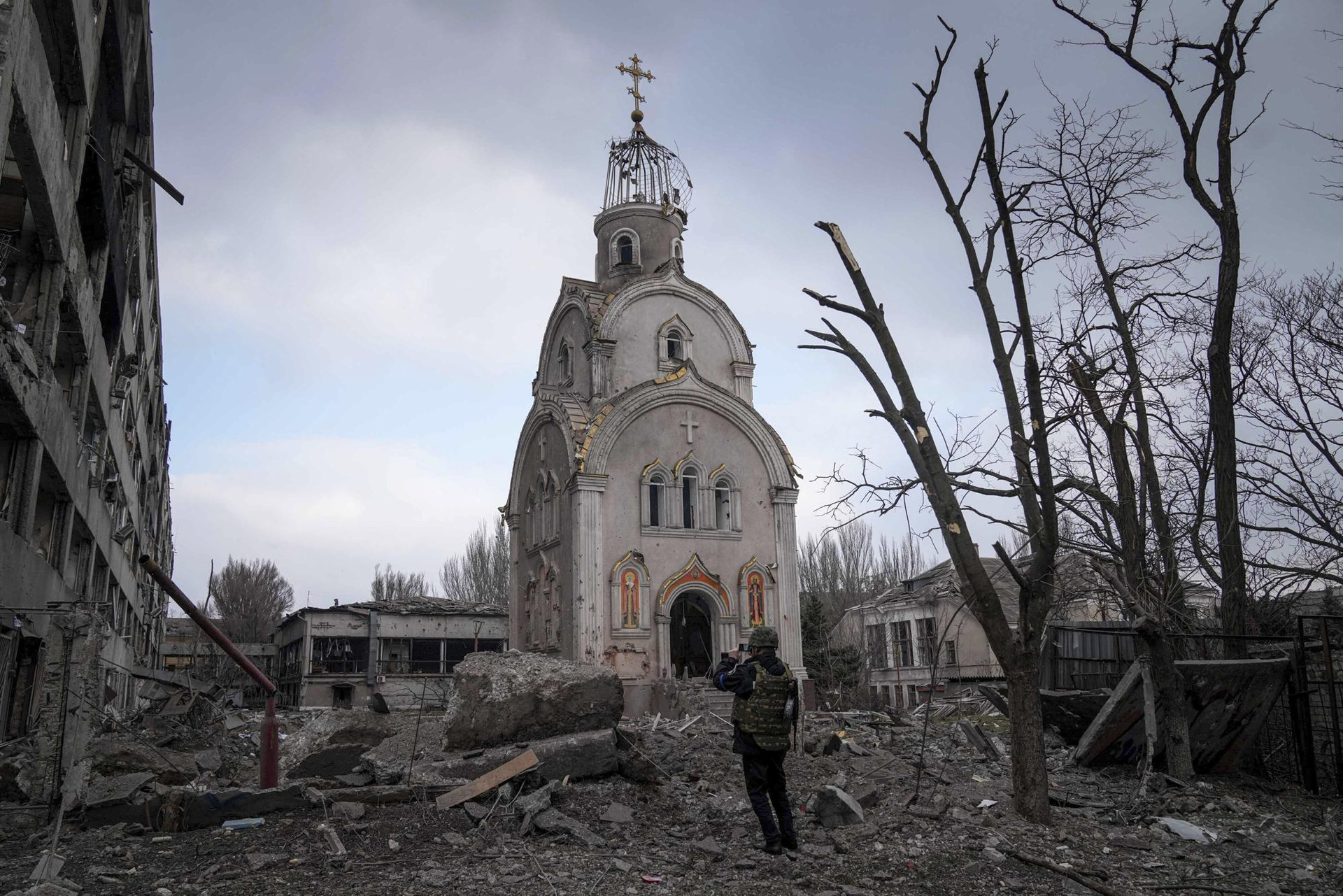 Binh sĩ Ukraine đứng trước một nhà thờ bị hư hại ở Mariupol, Ukraine. Ảnh: AP.