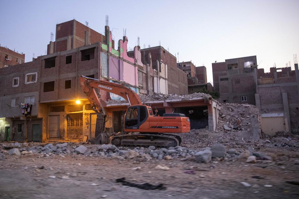 Một chiếc xe ủi phá hủy nhà cửa trong chiến dịch dự án lớn bao gồm xây dựng các thành phố, đường xá, cầu và đường hầm mới ở Cairo, Ai Cập. Ảnh: AP.