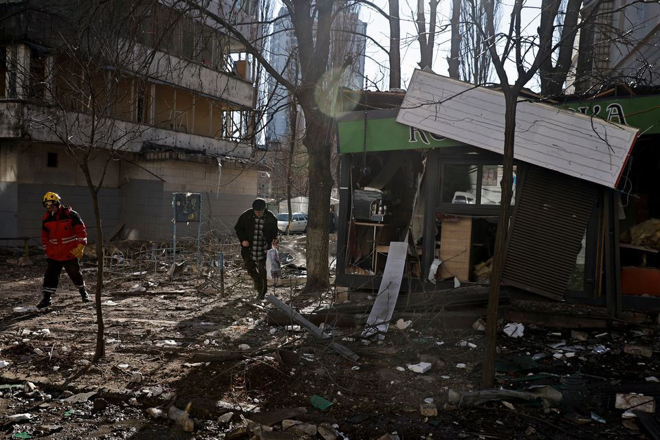 Người dân đi qua các mảnh vỡ cạnh một tòa nhà bị hư hại ở Kiev, Ukraine. Ảnh: Reuters.
