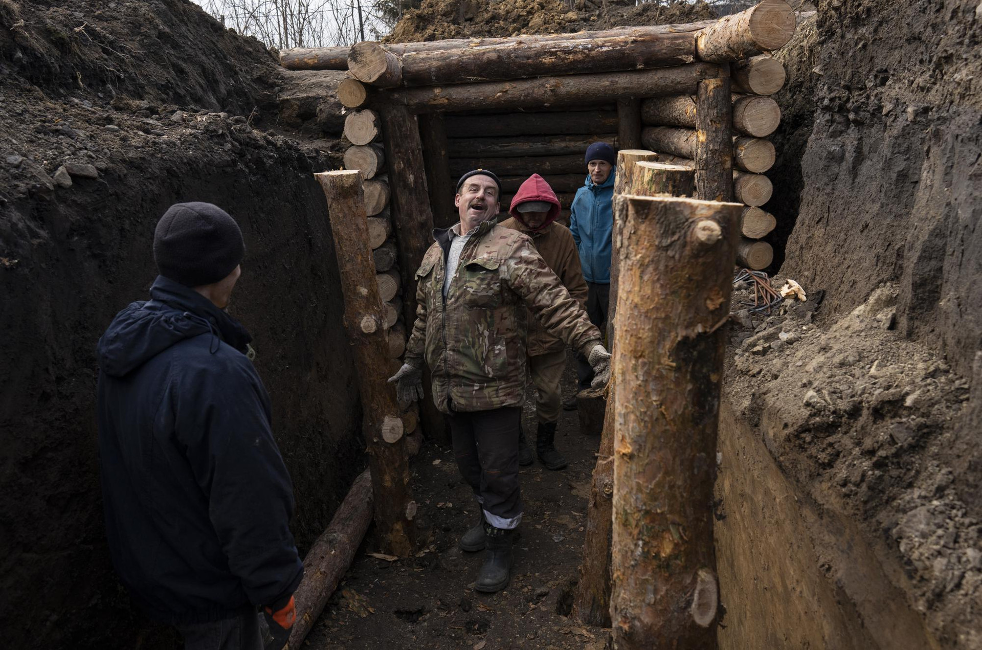 Những người đàn ông xây dựng chiến hào cùng binh lính ở Lityn, Ukraine. Ảnh: AP.