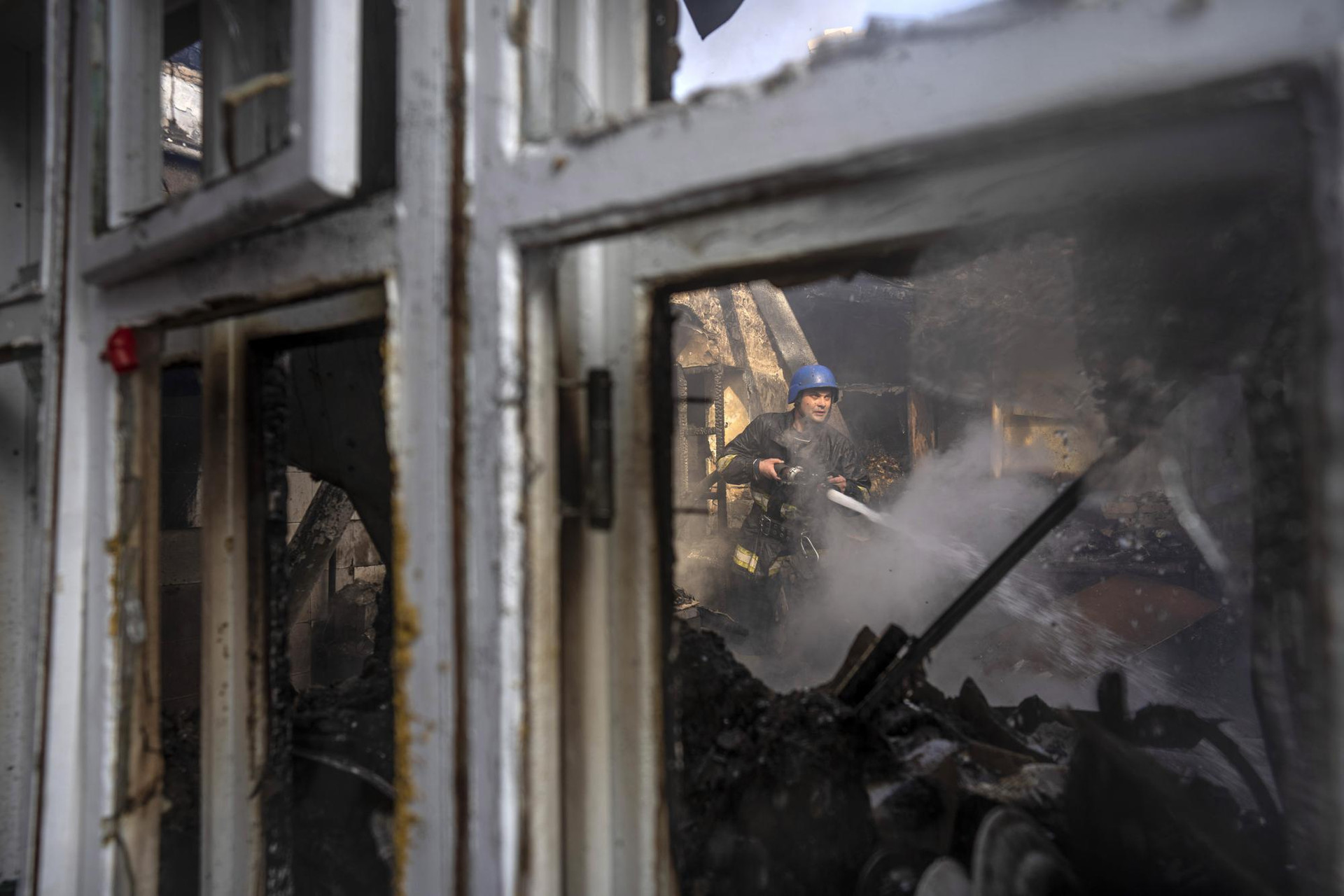 Lính cứu hỏa phun nước vào bên trong một ngôi nhà bị cháy ở thủ đô Kiev, Ukraine. Ảnh: AP.