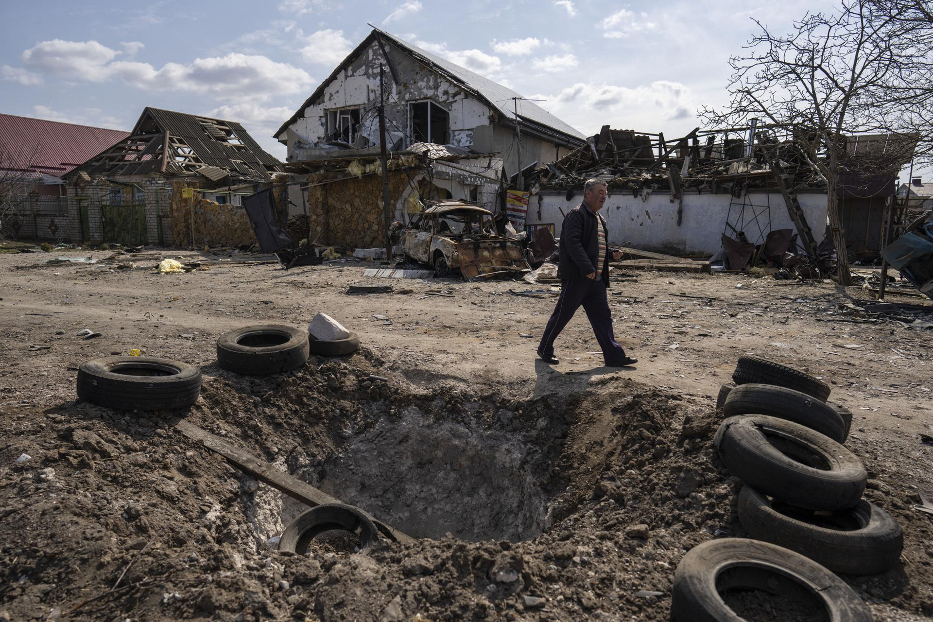Hố bom và những ngôi nhà bị hư hại ở ngoại ô Mykolaiv, Ukraine. Ảnh: AP.