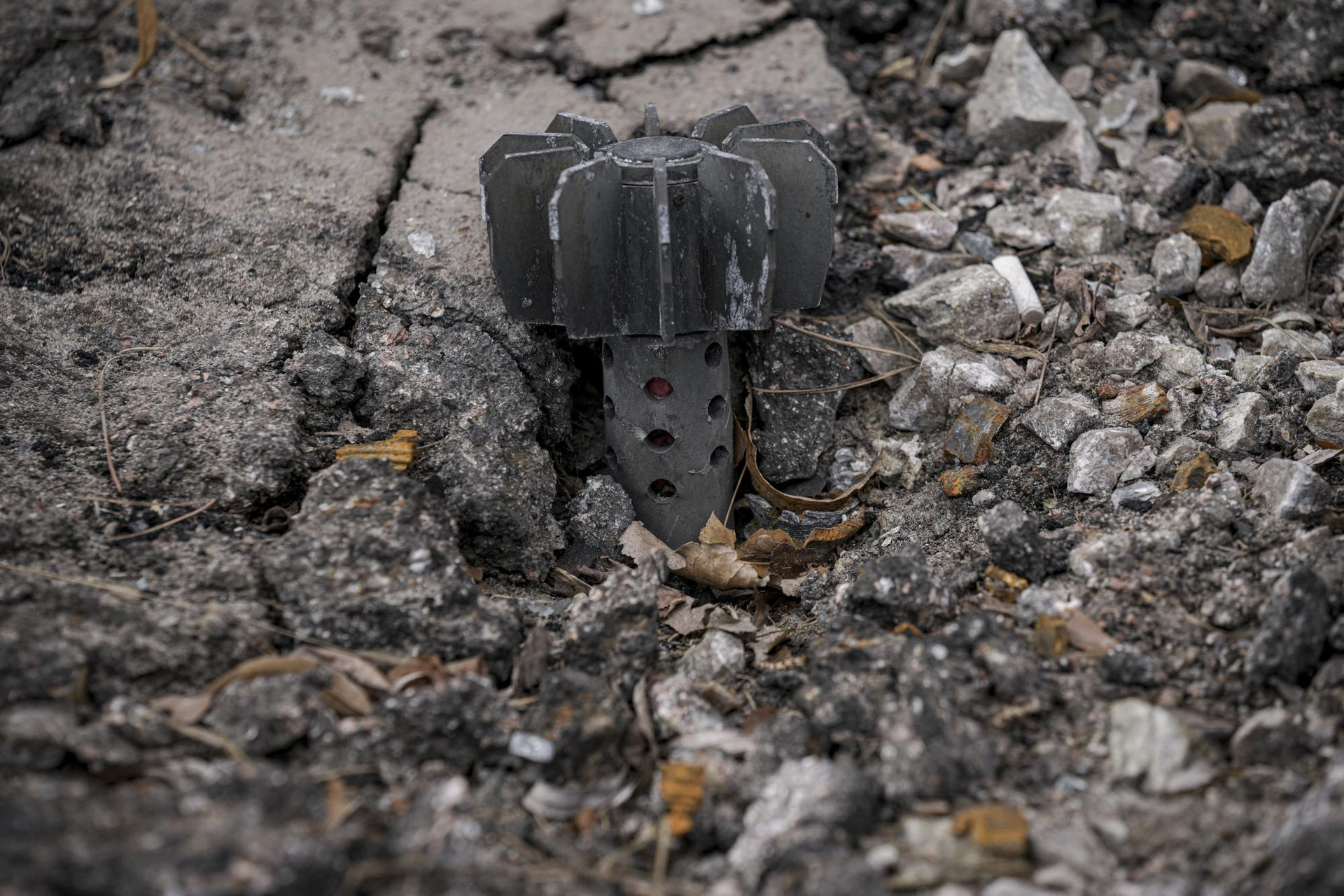 Một phần của quả đạn cối nhô ra khỏi đường nhựa ở Stoyanka, Ukraine. Ảnh: AP.