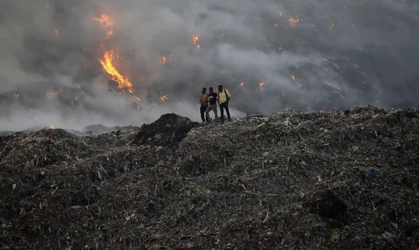 Người dân đứng tại bãi rác Ghazipur đang bốc cháy ở Delhi, Ấn Độ. Ảnh: The Guardian.