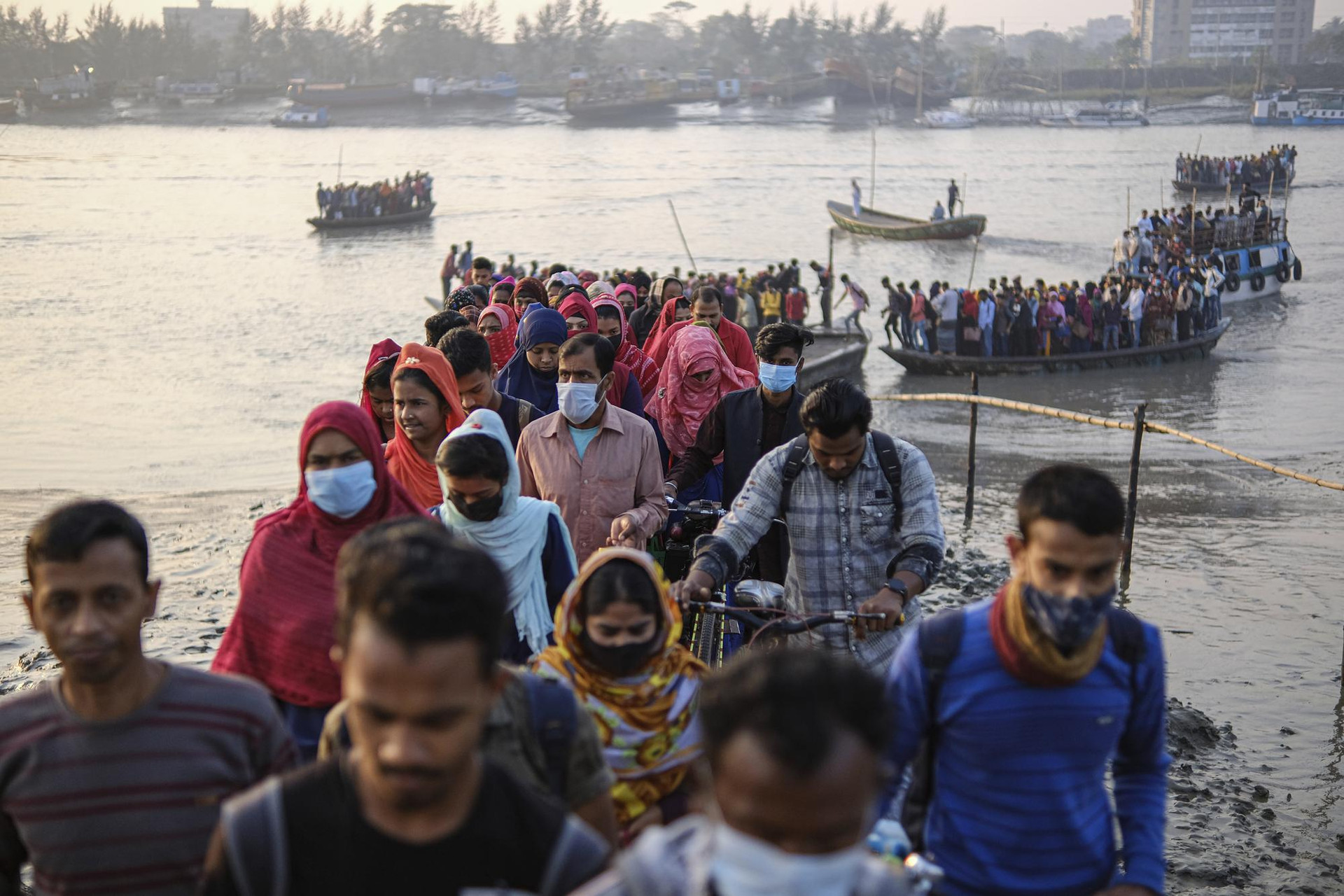 Công nhân đi bộ đến làm việc tại một khu chế xuất vào sáng sớm sau khi băng qua sông Mongla ở Mongla, Bangladesh. Ảnh: AP.