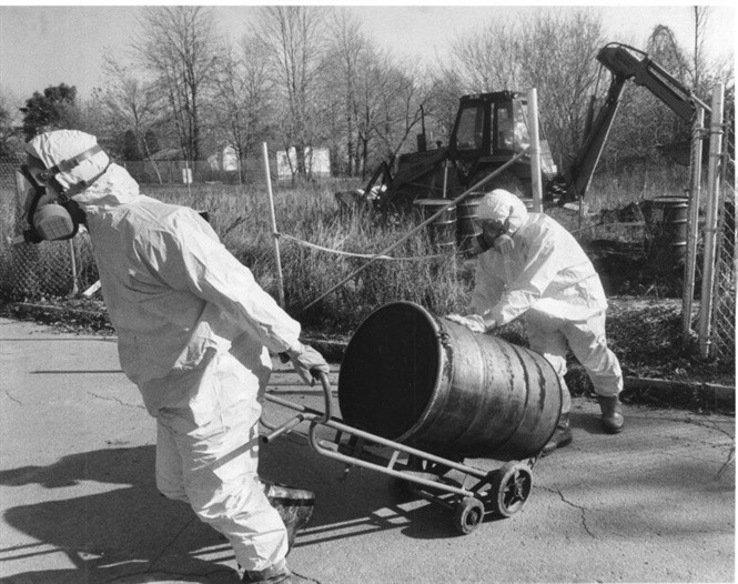 Công nhân mặc đồ bảo hộ kéo một thùng chứa đất nhiễm độc tại bãi thải nguy hại ở Love Canal năm 1988. Ảnh: Buffalo News.