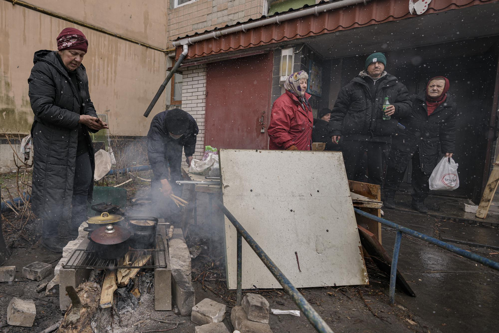 Người dân nấu ăn bên ngoài một tòa nhà chung cư không có điện, nước và khí đốt ở Bucha, Ukraine. Ảnh: AP.