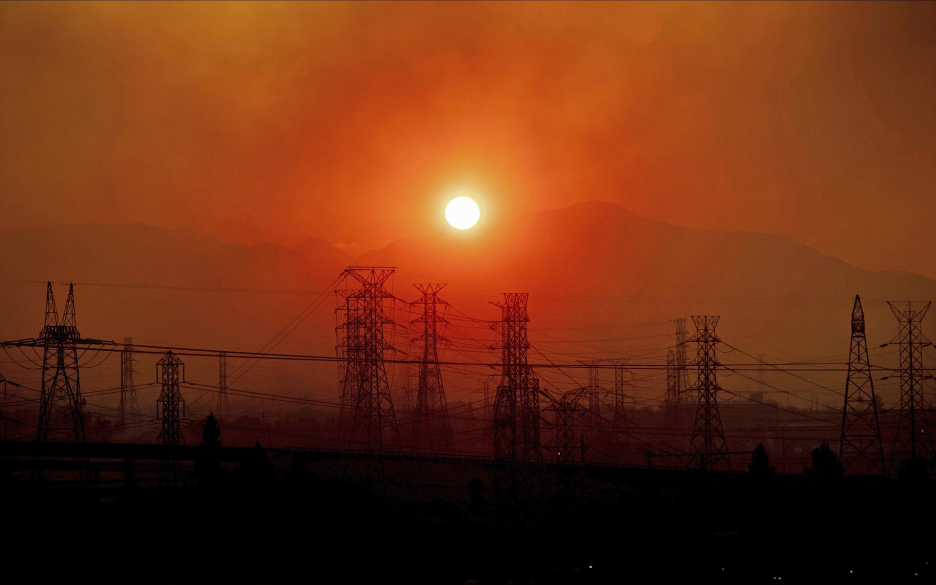 Khói từ đám cháy rừng Saddle Ridge bay lơ lửng trên các đường dây điện khi mặt trời mọc ở Newhall, bang California. Ảnh: AP.