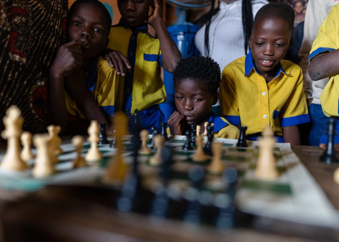 Những đứa trẻ tập trung bên bàn cờ vua. Ảnh: The Guardian.